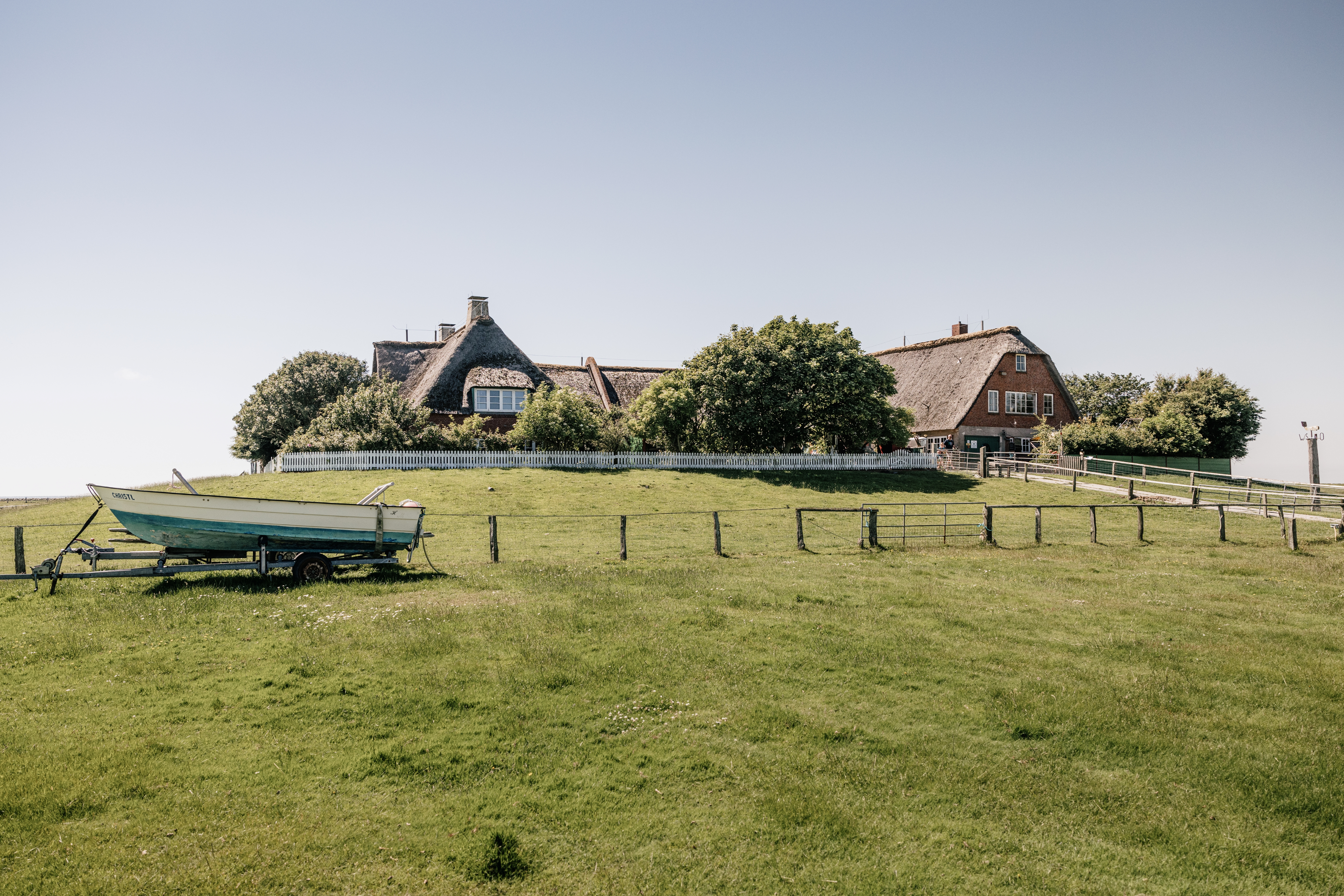 Haus auf Hallig Süderoog mit kleinem Holz-Ruderboot auf der Wiese