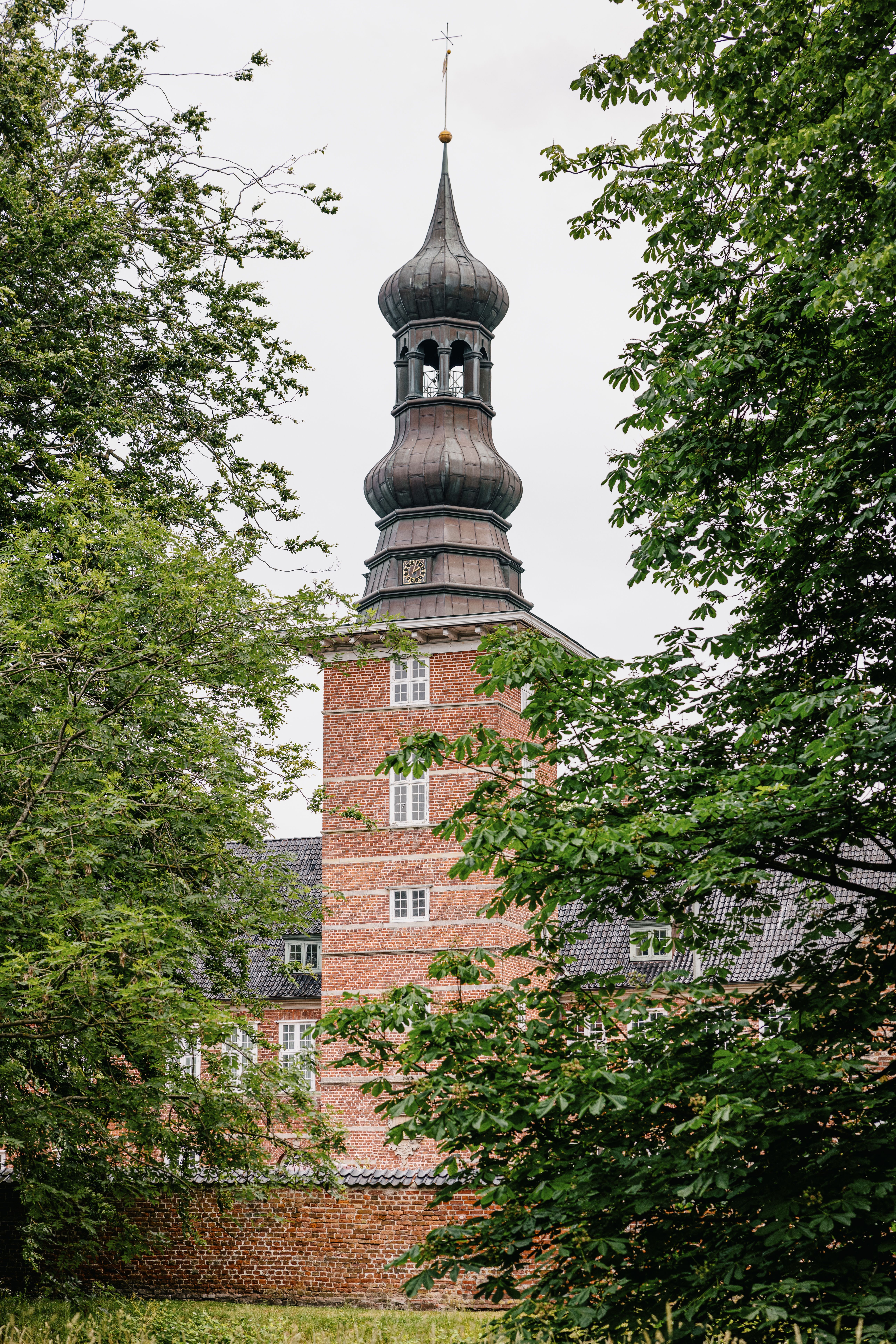 Blick auf den Turm des Husumer Schlosses, der ein wenig versteckt hinter Büschen liegt