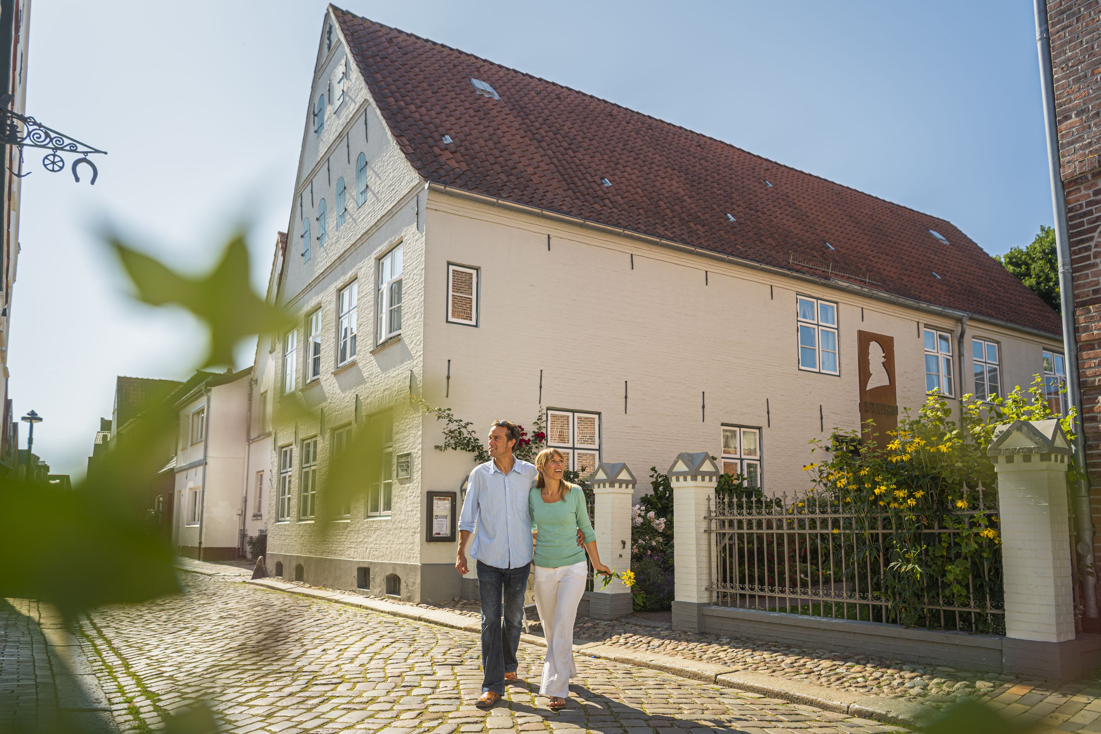 Ein Paar spaziert vor dem Husumer Stormhaus in Husum
